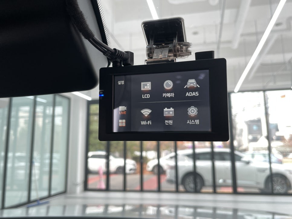 Dash camera mounted above a vehicle dashboard with infotainment screen below